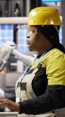 PC 'de yazan neşeli fabrika mühendisinin dikey video portresi, üretim hatlarının izlenmesini denetliyor. Endüstrideki neşeli kadın 4.0 fabrika teçhizatı en uygun verimlilikte çalışıyor.