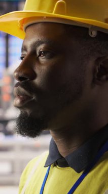 Sektör 4.0 'da yenilenebilir enerji üreten profesyonel test ekipmanlarının dikey videosu. Fotovoltaik 'teki Afrikalı Amerikalı adam. Akıllı fabrika, rutin teftiş, kamera A.