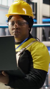 Sektör 4.0 fabrikasında çalışan dikey videolu kadın bakım prosedürlerini takip ederek defter kullanıyor. Akıllı fabrika çalışanı dizüstü bilgisayardaki verileri analiz ederek vites arızalarını öngörüyor, kamera B