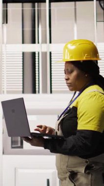 Dikey video uzmanı, yenilenebilir enerji üreten sanayi 4.0 tesisinde rutin teftişler yapmak için dizüstü bilgisayar kullanıyor. Fotovoltaik teknisyeni. Akıllı fabrika test ekipmanları. Not defteri kullanıyor.