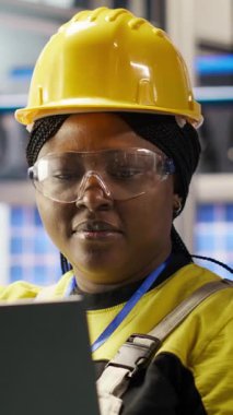 Dikey video uzmanı, yenilenebilir enerji üreten sanayi 4.0 tesisinde rutin teftişler yapmak için dizüstü bilgisayar kullanıyor. Fotovoltaik teknisyeni. Akıllı fabrika test ekipmanları. Not defteri kullanıyor.