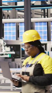 Dikey video akıllı fabrika mühendisi otomatik iş akışlarını ve kontrol sistemlerini bilgisayara aktarmak için dizüstü bilgisayar kullanıyor. Teknisyen sensörleri dizüstü bilgisayar ve kamera kullanarak üretime entegre ediyor.