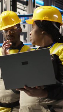 Dikey video mühendisliği ekibi, güneş paneli üretim ekipmanlarını denetliyor. Otomatik sanayi 4.0 fabrikasındaki fotovoltaik montaj sistemlerini koruyan takım arkadaşları