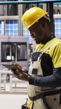 Dikey video mühendisi, tablet uygulaması kullanılarak güneş paneli üretim hatları ekipmanlarını denetliyor. İşçi dijital aygıt kullanarak otomatik sanayi 4.0 fabrikasında fotovoltaik montaj sistemleri sürdürüyor