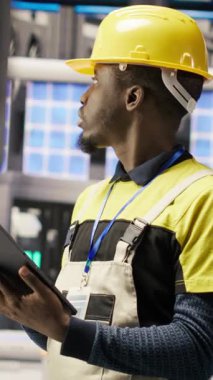 Dikey video akıllı fabrika uzmanı otomatik sistemleri test ediyor, operasyonel bütünlüğü izliyor. Endüstri 4.0 tesis teknisyeni hasar tespiti ve onarımı için ekipman, kamera B