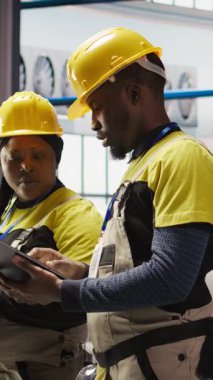 Dikey video akıllı fabrika mühendisliği ekibi otomatikleştirilmiş iş akışlarını ve kontrol sistemlerini uygulamak için beyin fırtınası yapıyor. Sanayi 4.0 fabrika iş arkadaşları sensörleri üretime entegre ediyor