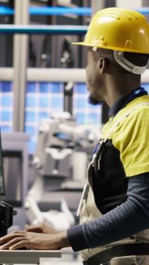 Dikey video mühendisi PC yazılımı kullanarak güneş paneli üretim hattı ekipmanlarını denetliyor. Otomatik endüstri 4.0 fabrikasında fotovoltaik montaj sistemlerini bilgisayar, kamera B kullanarak sürdüren işçiler