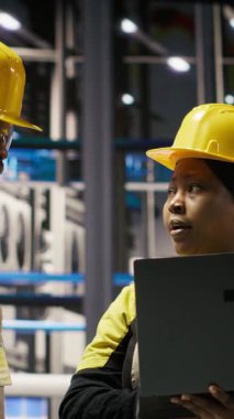 Dikey video mühendisliği ekibi akıllı fabrikada beyin fırtınası yapıyor, IoT sensör verilerini analiz ediyor. Fotovoltaik sistemlerin işlevsel güvenilirliğini yöneten sanayi 4.0 fabrika çalışma arkadaşları