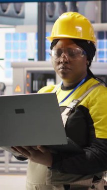 Dikey video mühendisi dizüstü bilgisayar kullanarak öngörüsel bakım yapıyor, IoT sensör verilerini analiz ediyor, akıllı fabrika ortamında fotovoltaik sistemlerin işlevsel güvenilirliğini yönetiyor, kamera A