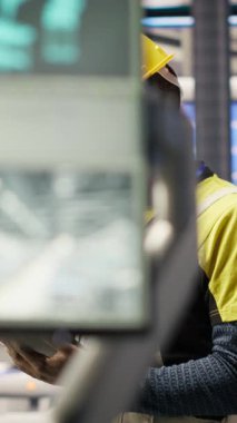 Dikey video mühendisi, tablet uygulaması kullanılarak güneş paneli üretim hatları ekipmanlarını denetliyor. İşçi dijital aygıt kullanarak otomatik sanayi 4.0 fabrikasında fotovoltaik montaj sistemleri sürdürüyor