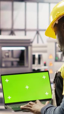 Akıllı fabrikadaki dikey video mühendisi IoT sensör verilerini analiz etmek için yeşil ekran dizüstü bilgisayar kullanıyor. Endüstri 4.0 bitkisel uzmanlık sistemi tanımlaması krom anahtar model defteri üzerinde çalışma süresini azaltmak için