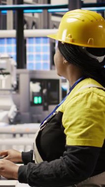 Fotovoltaik fabrikasında sistem performans ölçümlerine bakmak için bilgisayar ekranını kullanan dikey video mühendisi. IoT aracılığıyla enerji üretimini izlemek için bilgisayar ekranı kullanan 4.0 sanayii işçisi