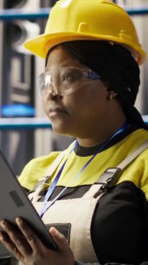 Dikey video akıllı fabrika mühendisi IoT sensör verilerini analiz etmek için tablet kullanıyor, ekipman işletim verimliliğini artırıyor. Endüstriyel fabrika işçisi üretimi azaltmak için sistem kontrolü yapıyor