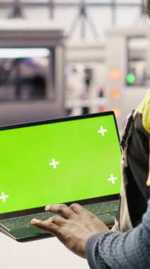 Dikey video güneş panelleri fabrika mühendisi vites arızalarını tahmin etmek için performans verilerini yeşil ekran laptopuyla analiz eder. Fotovoltaik fabrika işçisi bakım için model defter kullanıyor