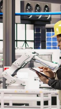 Dikey video teknisyeni güneş enerjisi kurulum sürecini denetliyor, otomatik makinelerin sorun çıkarması, yenilenebilir enerji üretim tesisinde robotik silahların kalibre edilmesi, kamera A