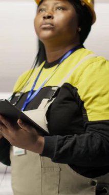 Dikey video mühendisi fotovoltaik fabrikasında yürüyor, tabletteki sistem performans ölçümlerine bakıyor. İşçi sektörü 4.0 fabrika işletiyor, IoT aracılığıyla enerji üretimini izlemek için aygıt kullanılıyor