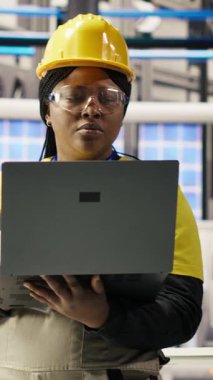 Dikey video mühendisi dizüstü bilgisayar kullanarak öngörüsel bakım yapıyor, IoT sensör verilerini analiz ediyor, akıllı fabrika ortamında fotovoltaik sistemlerin işlevsel güvenilirliğini yönetiyor, kamera B