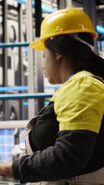 Dikey video akıllı güneş panelleri fabrika işçisi PC klavyesinde yazıyor, otomatik sistemleri test ediyor, bakım yapıyor. Endüstri 4.0 fotovoltaik fabrikasındaki kadın ekipmanları denetlemek ve tamir etmek için bilgisayar kullanıyor.