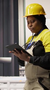 Dikey video mühendisi fotovoltaik fabrikasında yürüyor, tabletteki sistem performans ölçümlerine bakıyor. İşçi sektörü 4.0 fabrika işletiyor, IoT aracılığıyla enerji üretimini izlemek için aygıt kullanılıyor