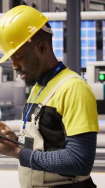 Güneş panelleri fabrikasındaki dikey video teknisyeni tablet kullanarak IoT sensör verilerini analiz ediyor. Fotovoltaik sistemlerin işlevsel güvenilirliğini yöneten sanayi 4.0 fabrika uzmanı