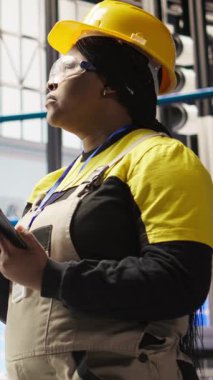 Dikey video akıllı fabrika mühendisi IoT sensör verilerini analiz etmek için tablet kullanıyor, ekipman işletim verimliliğini artırıyor. Endüstriyel fabrika işçisi üretimi azaltmak için sistem kontrolü yapıyor