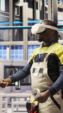 Sanal gerçeklik simülasyonunu kullanarak ekipman arızalarını öngören dikey video akıllı fabrika uzmanı. Sanayi 4.0 fabrika mühendisi bakım prosedürlerini izlemek ve hasar onarmak için VR kulaklık kullanıyor