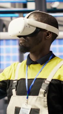 Akıllı fabrikadaki dikey video mühendisi VR kulaklık teknolojisi kullanarak bakım yapıyor. Sanal gerçeklik teknolojisi kullanarak fotovoltaik sistemlerin işlevsel güvenilirliğini yöneten sanayi 4.0 fabrika işçisi
