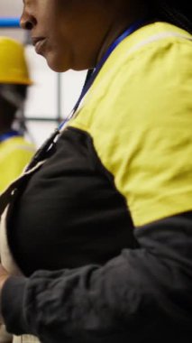 Akıllı güneş enerjisi üretim tesisinde dikey video mühendisi yüksek teknoloji makinelerini ayarlıyor ve sensör verilerini analiz ediyor. Mühendis sorun çıkaran fotovoltaik montaj ekipmanı, kamera.