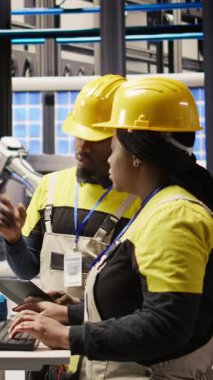 Dikey video mühendisliği ekibi akıllı fabrikada bilgisayar kullanarak robot montaj hatlarını denetliyor ve imalat sırasında kalite kontrolü sağlıyor. Takım çalışma arkadaşları otomatik taşıma bantlarını izler