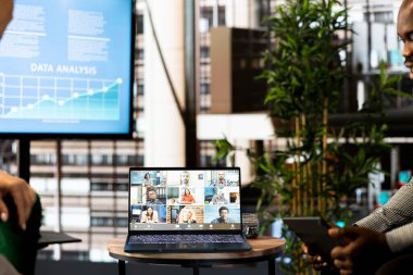 Afrika kökenli Amerikalı yönetici evden çalışan işbirlikçilerle tartışıyor, video konferansı yapıyor, dizüstü bilgisayarla yeni projeyi sunuyor. Videodaki işçilerle sohbet eden bir adam