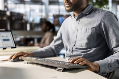 İş adamı, iş yerindeki bilgisayarında performans ölçümlerini analiz ediyor. Stratejik planlamayla ilgilenirken, şirketin başarılı sonuçlara yönelik hedeflerini desteklemek amacıyla verileri gözden geçirir..