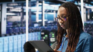 Gülümseyen sunucu odası mühendisinin portresi yapay zeka veri analizi grafiklerini yorumlamak için bir cihaz kullanıyor. Sistem ölçümlerini gösteren yapay zeka aracı kullanan mutlu veri merkezi çalışanı, kamera B