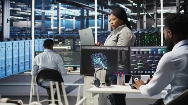 Sistem sağlığını optimize etmek için yapay zekayı kullanan neşeli sunucu merkezi teknisyeninin portresi. Neşeli veri merkezi bilişim uzmanı düğüm ağacı araçları kullanarak dişli sorunlarını analiz ediyor, kamera A