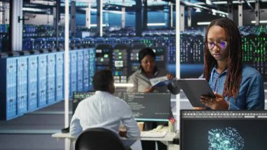 Gülümseyen sunucu odası mühendisinin portresi yapay zeka veri analizi grafiklerini yorumlamak için bir cihaz kullanıyor. Sistem ölçümlerini gösteren yapay zeka aracı kullanan mutlu veri merkezi çalışanı, kamera A