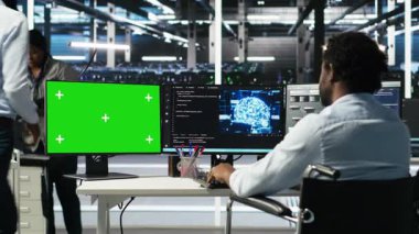 Belden aşağısı felçli bir veri merkezi çalışanı yeşil ekran PC kullanarak ağaç programlaması yapıyor. Özürlü sunucu merkezi yönetimi, veri kalıplarını tanımlamak için görsel programlama kullanır, kamera B