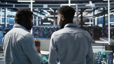 Sunucu merkezi mühendislik ekibi yapay zeka veri analizi grafiklerini yorumluyor. Öngörü sistemi ölçümleri gösteren yapay zeka programı kullanan takım çalışması veri merkezi meslektaşları, kamera A