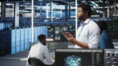 Veri merkezi mühendisi yapay zeka veri analizi grafiklerini yorumlamak için tablet kullanıyor. Sunucu odası çalışanı yapay zeka kullanarak sistem performans tahmin ölçümleri, kamera A