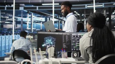 Veri merkezi sistem yöneticisi düğüm ağacı araçları kullanarak altyapı sorunlarını analiz ediyor. Sunucu merkezindeki adam, sistem sağlığını optimize etmek için yapay zeka görselleme bilgilerini kullanıyor. Kamera A.