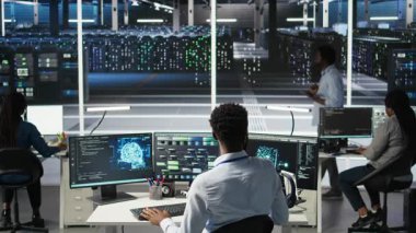 Donanımı yapılandırmak için yapay zeka sinir ağı modelleri kullanan veri merkezi yöneticisi. Adam sunucu odasında yapay zeka programlama dili üzerinde çalışıyor, sistem işlevselliğini optimize ediyor, kamera A