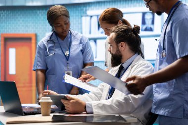 Doktorlar tedavi planlarını geliştirmek için insan anatomisi taramalarını inceleyip potansiyel teşhisi tartışıyorlar. Lisanslı sağlık uzmanları sigorta hizmetleri sağlamak için birlikte çalışıyorlar.