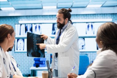 Doktor ve tıbbi ekibi teşhis için radyografi verilerini ve hastane kayıtlarını incelemek üzere bir ofiste buluşuyorlar. Röntgen, analitik ve tedavi planları üzerinde çalışan lisanslı sağlık görevlileri, test sonuçları.