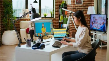 Uzman sanatçı kadın yaratıcı bir ofiste bilgisayarında dijital fotoğrafları düzenliyor. Düzenleme yazılımıyla donatılmış çalışma alanı, endüstrideki sanatsal çalışmaları geliştiriyor. Kamera A.