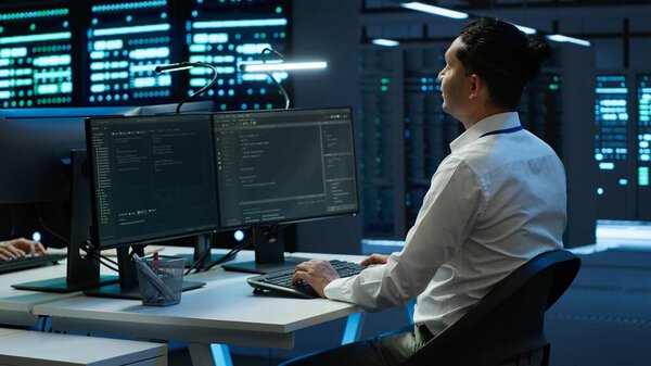 Developer and coworker overseeing data center, making improvements and updates to ensure system can handle networking tasks. Teamworking colleagues in server room tracking network traffic, camera A