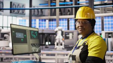 Endüstriyel santraldeki gülümseyen teknisyenin portresi güneş enerjisi kurulum sürecini denetliyor. Otomatik robotik kolları ayarlayan yenilenebilir enerji üretim tesisinde mutlu bir işçi, kamera A