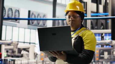 Sektör 4.0 fabrikasında çalışan bir kadın, bakım prosedürlerini takip ederek defter kullanıyor. Akıllı fabrika çalışanı dizüstü bilgisayardaki verileri analiz ederek vites arızalarını öngörüyor, kamera B