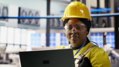 Uzman, yenilenebilir enerji üreten sanayi 4.0 fabrikasında rutin teftişler yapmak için dizüstü bilgisayar kullanıyor. Fotovoltaik teknisyeni akıllı fabrika test ekipmanları Not defteri, kamera B kullanarak