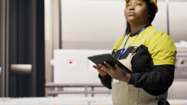 Mühendis fotovoltaik fabrikasında yürüyor, tabletteki sistem performans ölçümlerine bakıyor. İşçi sektörü 4.0 fabrika işletiyor, IoT sensörleri, kamera B ile enerji üretimini takip etmek için aygıt kullanıyor.