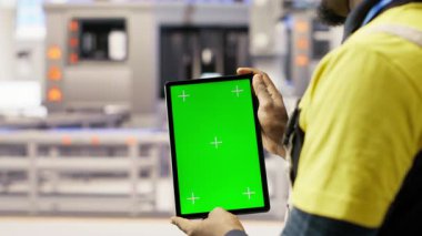 Akıllı fabrikadaki mühendis, yeşil ekran tablet kullanarak kalite kontrolü sağlayan robot montaj hatlarını denetliyor. İşçi otomatik taşıma sistemlerini krom anahtar aygıtı kullanarak izliyor, kamera B kapatma