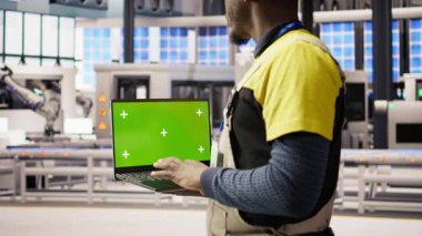Fabrika mühendisi yüksek teknoloji makinelerini ayarlamak ve sensör verilerini analiz etmek için yeşil ekran dizüstü bilgisayar kullanıyor. Endüstriyel fabrika çalışanı, montaj ekipmanlarında sorun çıkarmak için krom anahtar defteri kullanır, kamera A