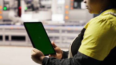 Fabrikadaki mühendisin bakım için kullandığı yeşil ekran tabletini kapatın, IoT sensör verilerini analiz edin. Renkli anahtar cihazı kullanarak fotovoltaik sistemleri yöneten endüstriyel fabrika işçisi, kamera B